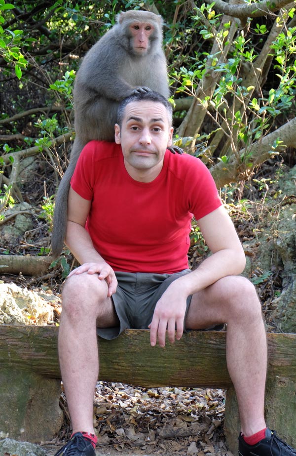 Tony assis avec un singe sur la tête.